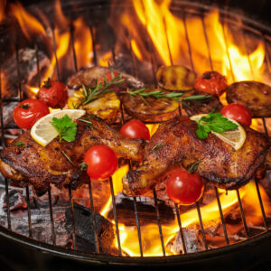 Grilled chicken legs on the flaming grill with grilled vegetable
